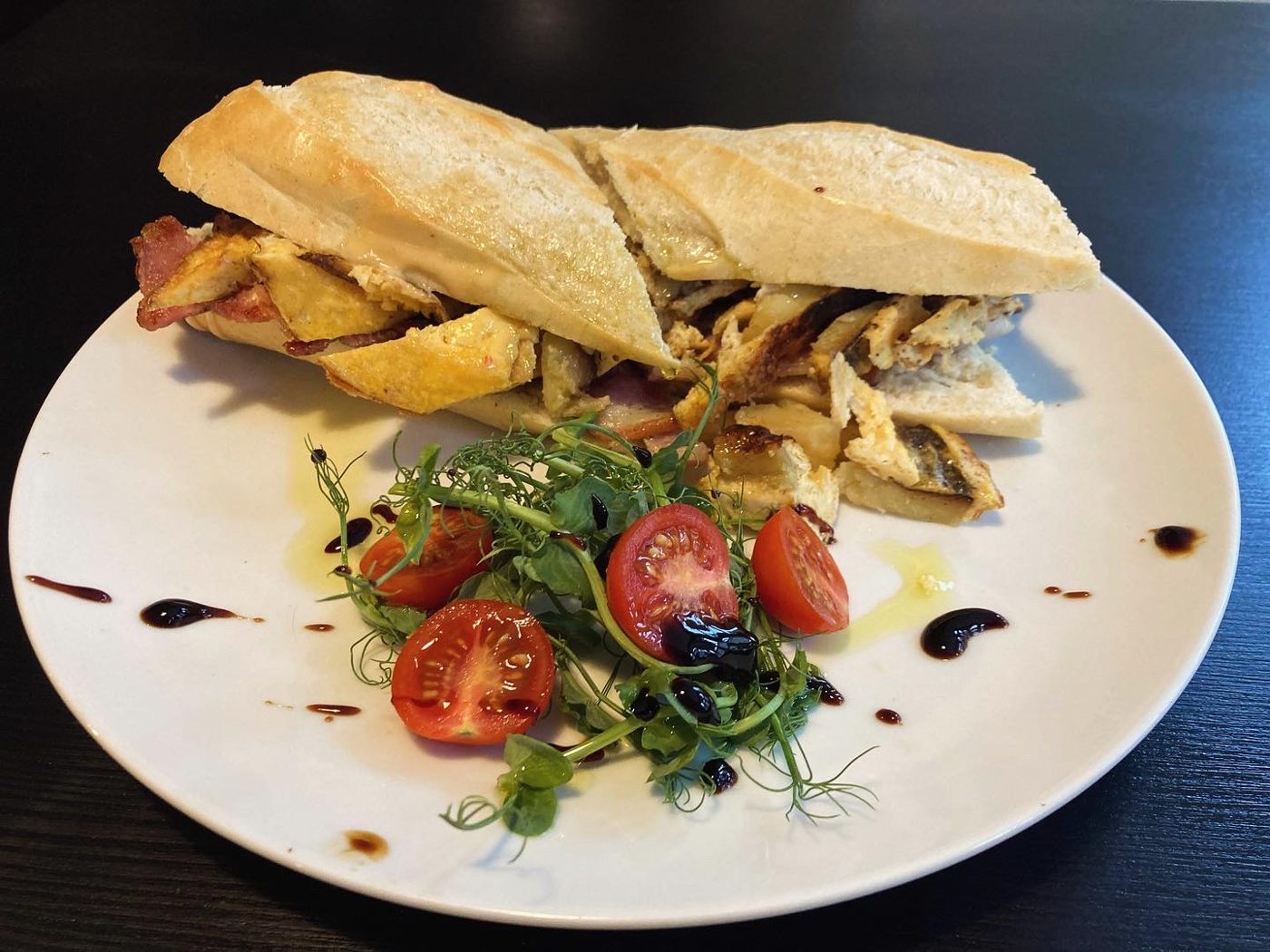A toasted baguette with rocket and tomatoes