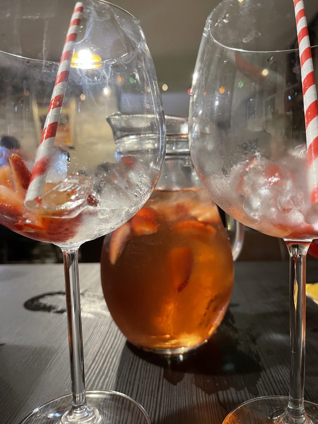 A jug and glasses of an orange drink with striped straws